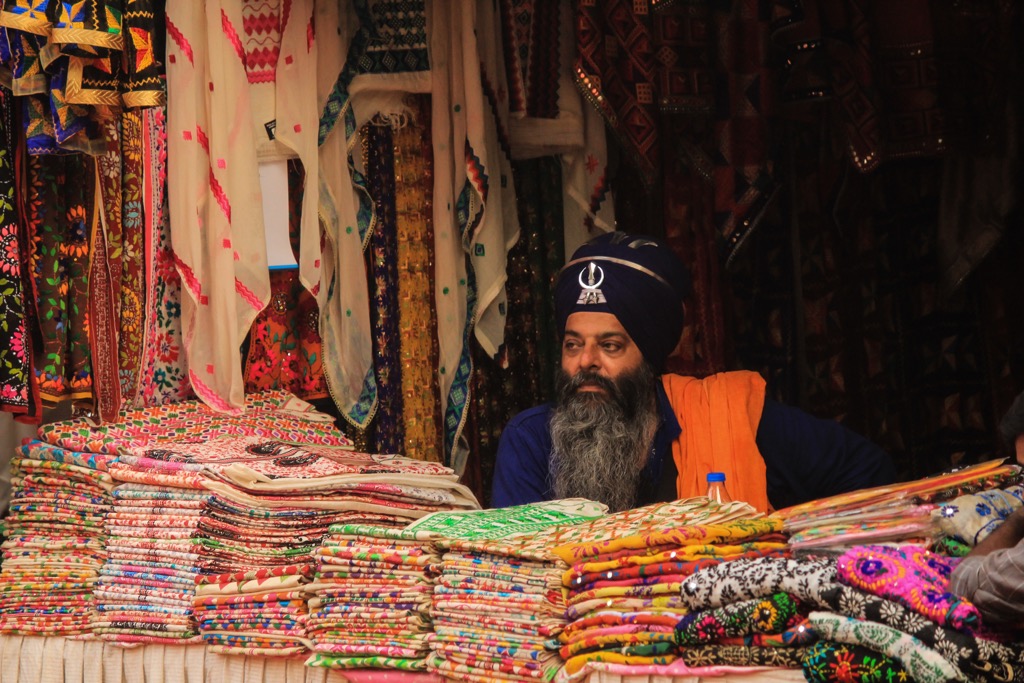 A Sikh man waits for customers at a market. Punjab Mountains