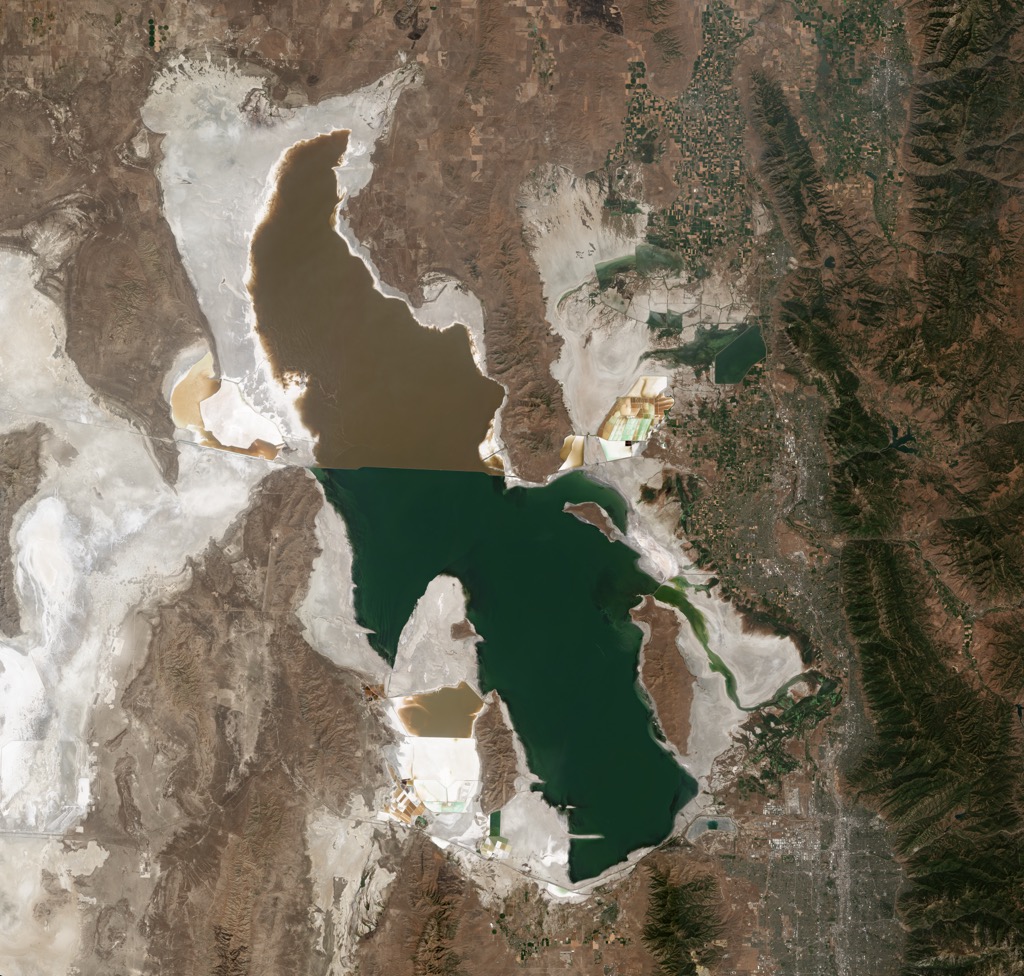 A 2018 satellite image of the Great Salt Lake at record low water levels. The dry lake bed is seen in white, while the difference in colors in the lake is due to a railroad causeway. The cities of the Wasatch Front are to the right of the lake, with the mountains in green further to the right. Weber County
